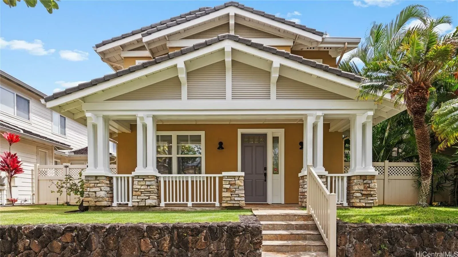 Front of the Aloha Kai home with covered porch and lava rock wall